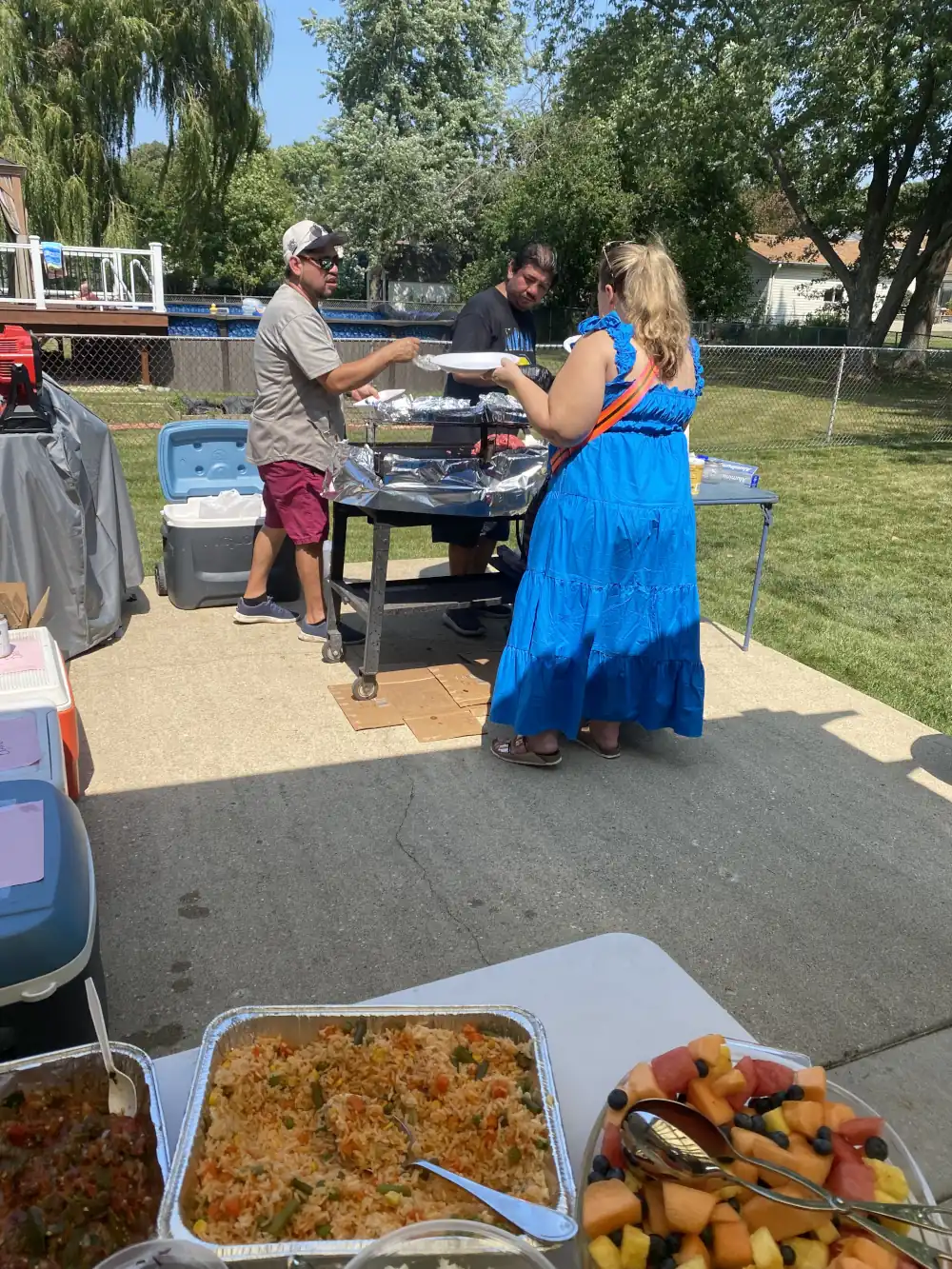 A Hispanic man serving grilled food to a blonde woman in a blue dress.